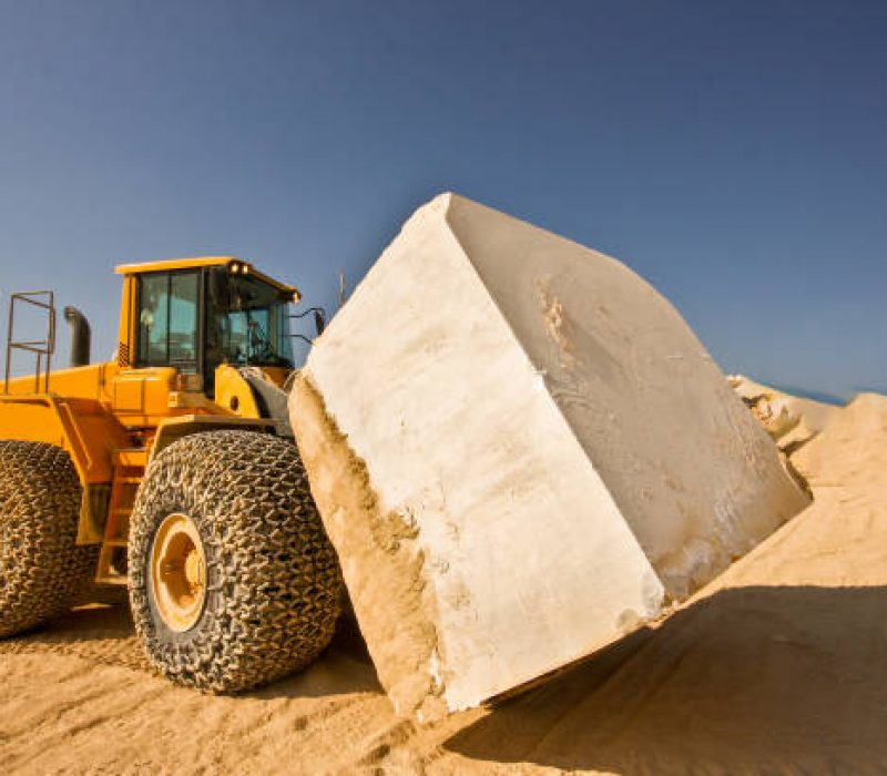 Bulldozer carrying oversized marble block in quarry